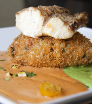 Grilled ling cod served with a tomato chipotle cream sauce, cilantro cream, and a California rice cake.