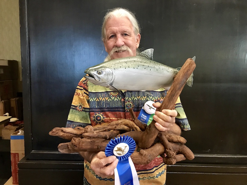 artist holding salmon woodcarving and blue ribbon