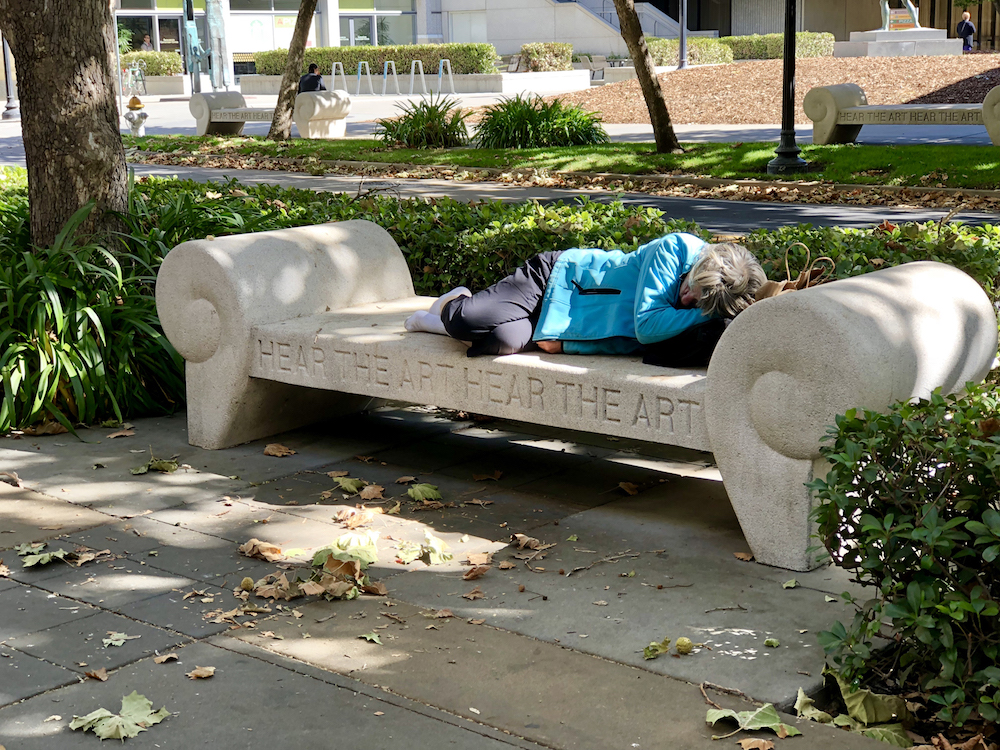homeless woman sleeping on bench